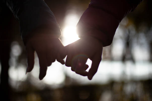 Close-up of cropped hands holding pinky promise. Close-up of hands hooking pinky promise against sunlight. pinky finger stock pictures, royalty-free photos & images