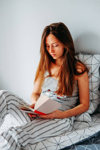 istock Young redhead woman reading in bed. Lazy moring routine. 1206902487