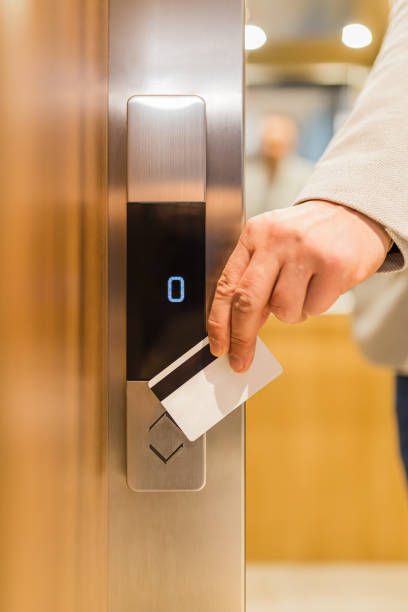 istock Man holding key card on sensor to open elevator door in modern building or hotel. 1206902495