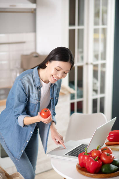 istock Happy young woman with a tomato in hand. 1206902905