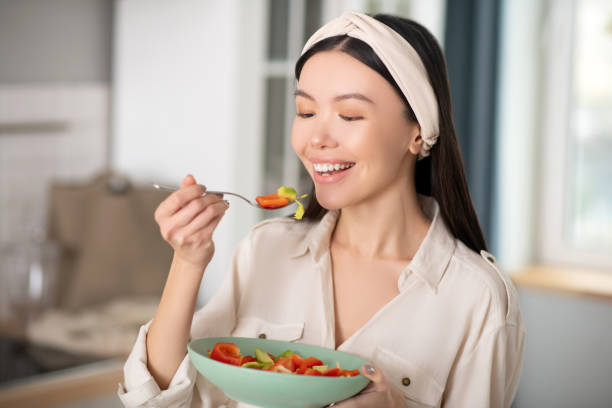 istock Beautiful joyful young lady eating vegetable salad. 1206903518