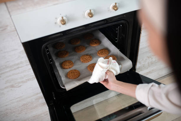 istock Female hand taking out baking sheet from the oven. 1206903673