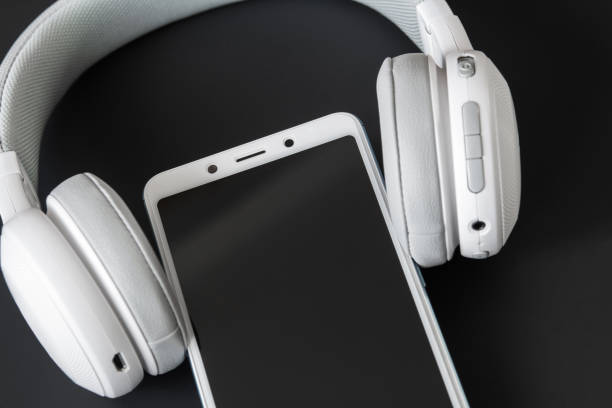 istock Wireless headphones and smartphone. Dark background, closeup, selective focus 1206904484