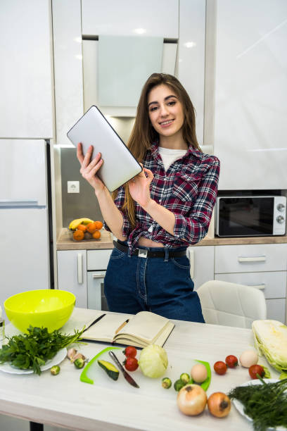 istock Young woman using a tablet computer to cook different vegetables in her kitchen for everything about healthy nutrition. 1206905276