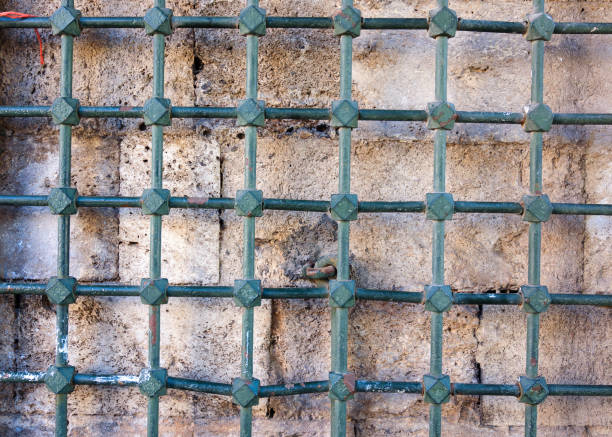 istock An old stone wall behind a metal grate. 1206907219