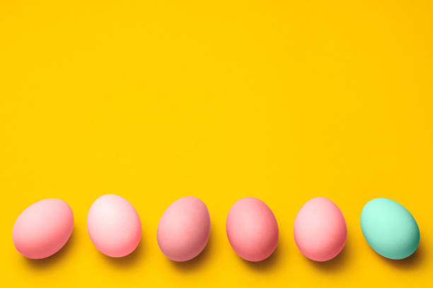 istock easter eggs painted in pastel pink color on a yellow background with copyspace on top. happy holiday 1206907462