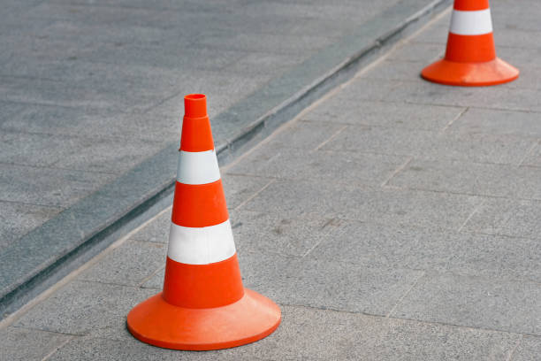 istock Two road cones on a square gray tile. Orange cones with white stripes 1206908769
