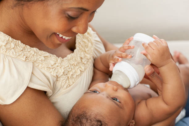 istock Smiling mom feeding her baby daughter on the sofa 1206909946