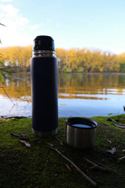 istock Thermos Vacuum flask in forest and lake. Close up 1206912070