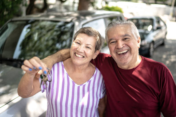 Portrait of senior couple showing car key in front of they new car Portrait of senior couple showing car key in front of they new car car ownership photos stock pictures, royalty-free photos & images