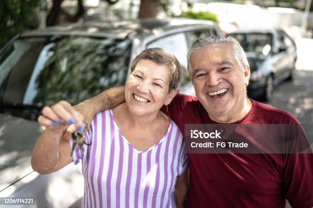 Portrait Of Senior Couple Showing Car Key In Front Of They New Car Stock Photo - Download Image Now