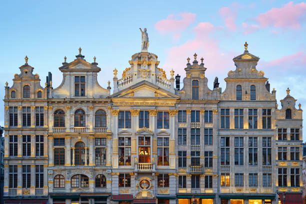 North-eastern part of Grand Place central square in Brussels, Belgium. Sunset evening view of row of old beautiful stone buildings facades between Rue de la Colline and Rue des Harengs. Lots of artistic golden details and decorations. stock photo