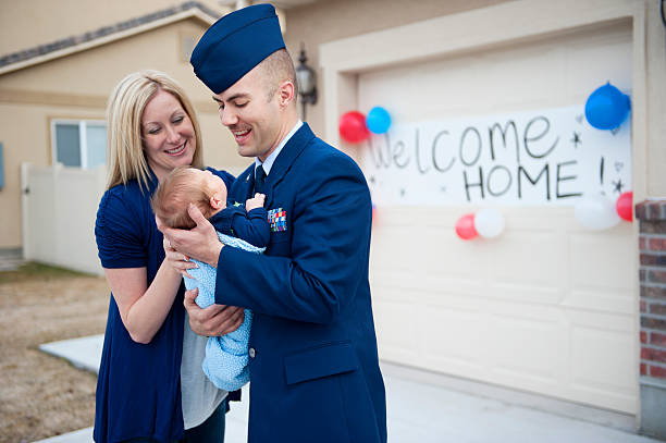 Meeting the baby An armed forces soldier is welcomed home by his wife and new baby.  air force stock pictures, royalty-free photos & images