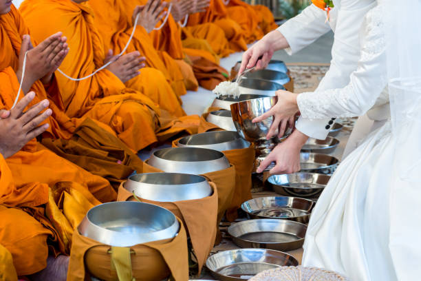 ofrezca comida al monje. el novio da comida a la limosna a un monje budista en la ceremonia de boda tradicional tailandesa. mano mientras pone ofrendas de comida en el cuenco de limosna de un monje budista. los budistas ofrecen comida en cuencos. - part of buddha fotografías e imágenes de stock