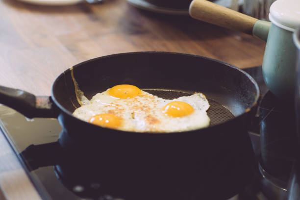 istock Fried eggs in the pan for breakfast. Cooking breakfast with fried eggs and toast in the kitchen 1206920890