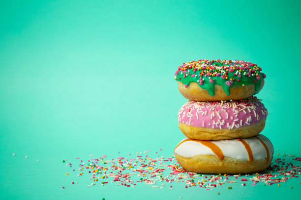 istock Donuts (doughnuts) of different colors on a green background with multi-colored festive sugar sprinkles. Holiday and sweets, baking for children, sugar concept 1206924942