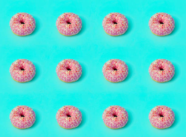 istock Donuts (doughnuts) of different colors on a green background with multi-colored festive sugar sprinkles. Holiday and sweets background. Minimal concept 1206924951