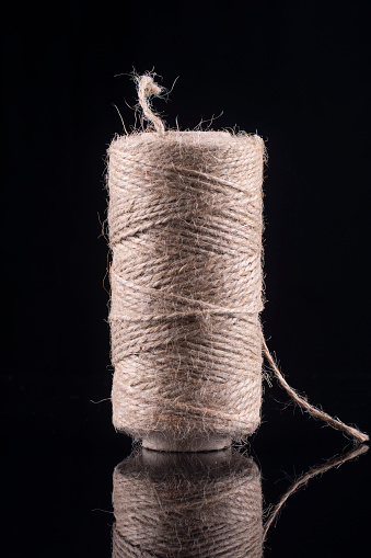 Skein of flax thread on a black background. Vertical photo.