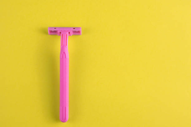 istock Pink plastic razor on a yellow background. Free space for an inscription. 1206925174