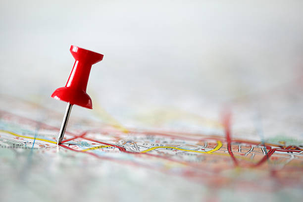 Pushpin on map Red pushpin showing the location of a destination point on a map pinning stock pictures, royalty-free photos & images
