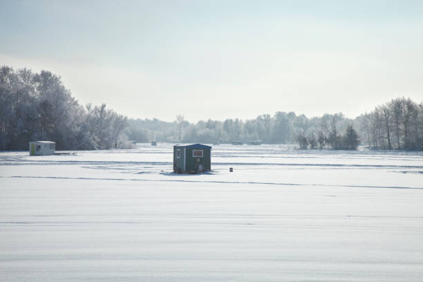 Ice fishing shacks at a Minnesota lake on a bright winter morning Ice fishing shacks and trailers at a Minnesota lake on a bright winter morning ice fishing stock pictures, royalty-free photos & images