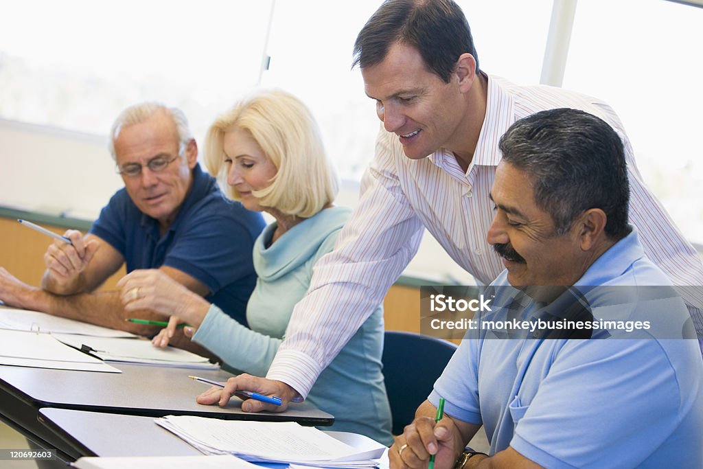 Teacher assisting mature student in class Teacher assisting mature student with work in class Nontraditional student Stock Photo