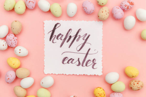istock Happy Easter concept. Inscription HAPPY EASTER letters candy chocolate eggs and jellybean sweets isolated on trendy pastel pink background. Simple minimalism flat lay top view copy space 1206930138