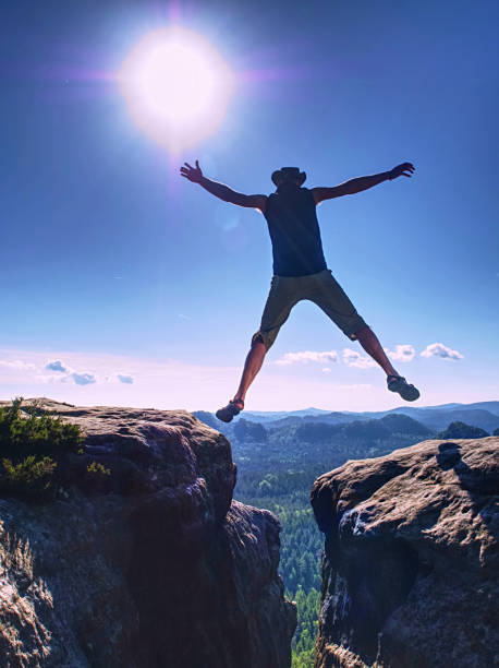 istock Hiker with cowboy leather hat jumps from big rock against sunset 1206930525