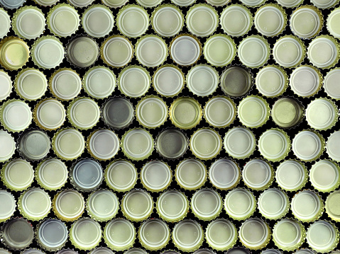 Background of large number of inverted metal bottle caps. Top view. Alcohol pub, beer drinking, beverage concept.