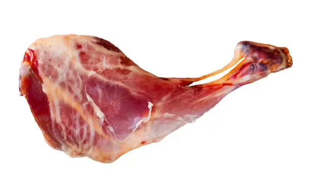Raw meaty leg of baby goat with ingredients for cooking on wooden background. Isolated over white background