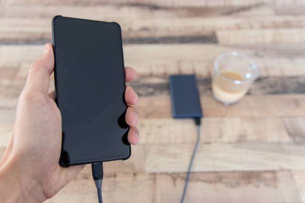 istock Hand holding phone connected to power bank 1206942822