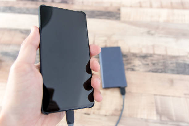 istock Hand holding phone connected to power bank 1206942835