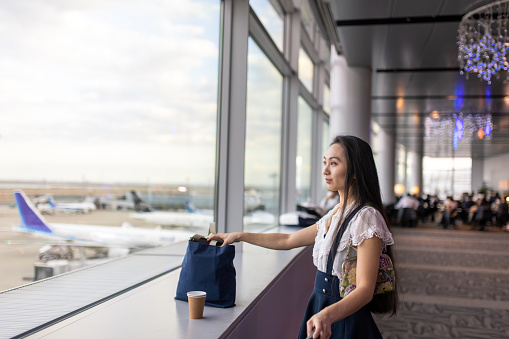 Young Asian woman looking at airplanes from airport observation deck