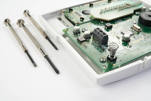 istock Home alarm control panel repairing. Open Electronic board panel with screwdrivers on a white background. 1206944535