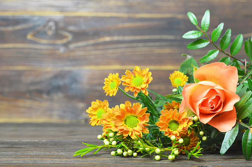 Close up color image depicting a woman holding a bouquet of orange gerbera daisy flowers.