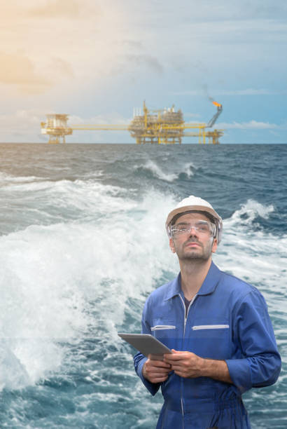 istock staff worker with tablet in hand and offshore rig background concept. 1206948282