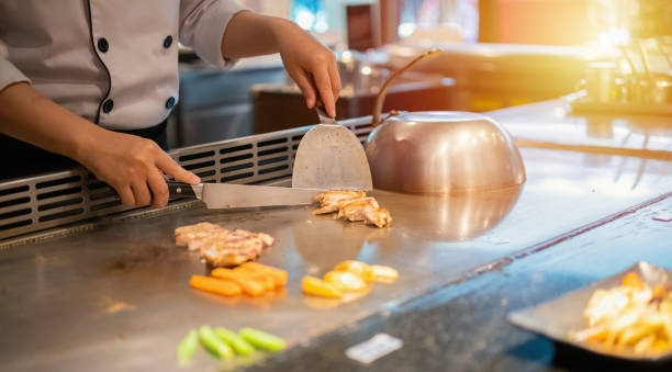 chef japonés cocinando carne en el restaurante teppanyaki - teppan yaki fotografías e imágenes de stock