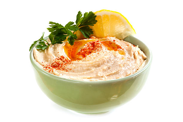 Bowl of hummus with cilantro and lemon Bowl of hummus, with olive oil and paprika, isolated on white. hummus stock pictures, royalty-free photos & images