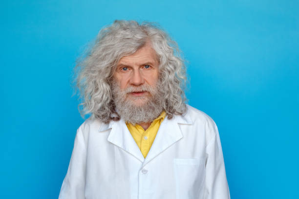 istock Old man wearing doctor's gown studio isolated on blue looking camera thoughtful 1206955587
