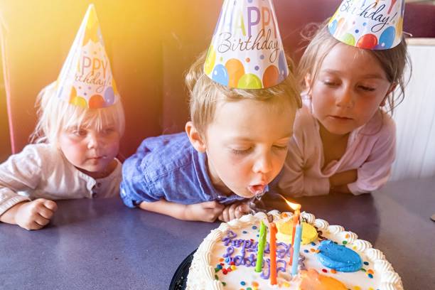 誕生日ケーキのろうそくを吹く誕生日を祝う子供たち - birthday family party cake ストックフォトと画像