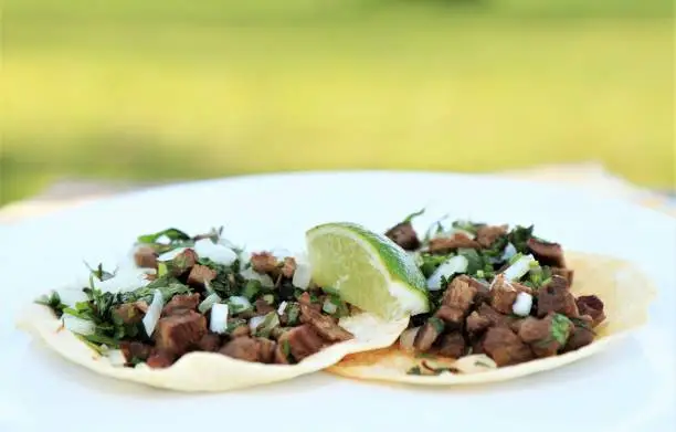 2 authentic Mexican steak (asada) tacos with lime, cilantro, and onions