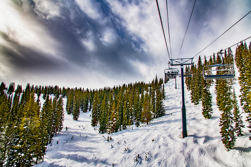 A ski lift up the side of a mountain at Winter Park, Colorado as a storm starts to roll in on a cold winter afternoon.