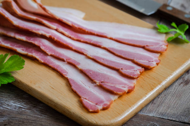 istock Raw sliced bacon on wooden board 1206967476