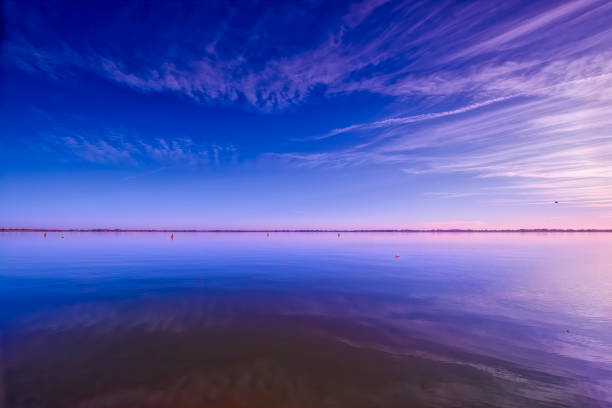 Serene lake at sunset with fishing equipment in view, featuring a tranquil atmosphere and picturesque reflections of lights and a mountain in the background.