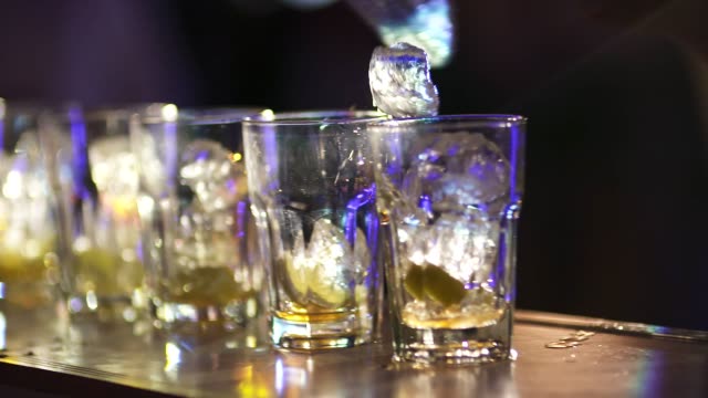 barman putting ice into glass