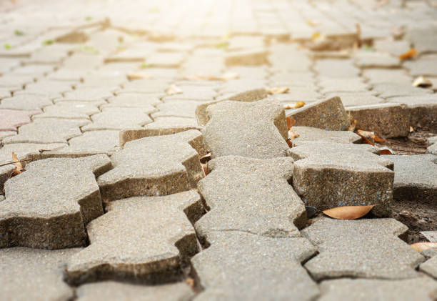 the floor of the footpath is broken. the footpath is uneven.may cause people to stumble and fall. - uneven imagens e fotografias de stock