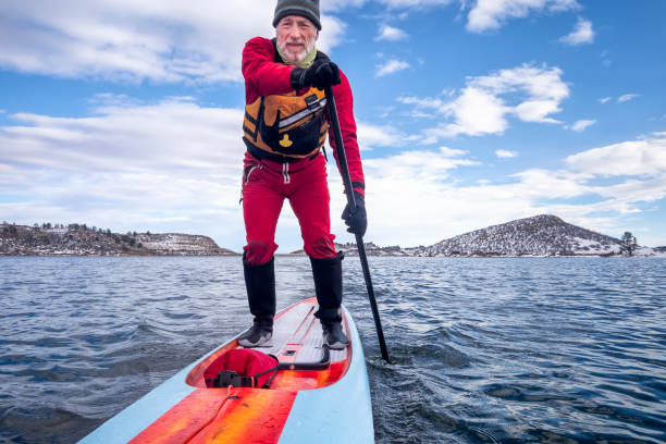 istock active senior is paddling stand up paddlenboard in winter 1206976270