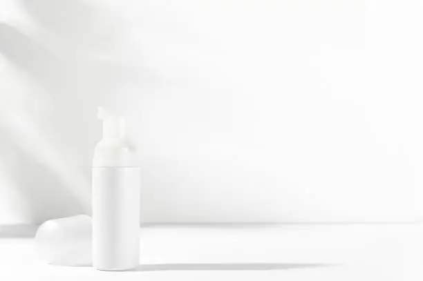 Facial, body care cosmetics bottle with dispenser. White unbranded flacon on light mockup. Blank package for nourishing or moisturizing foam, lotion, cream, balm. Skincare product advertising concept.