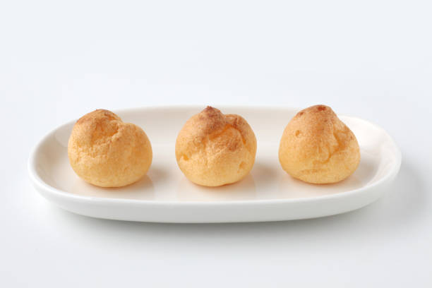 istock cream puffs on plate closeup isolated on white background 1206979832