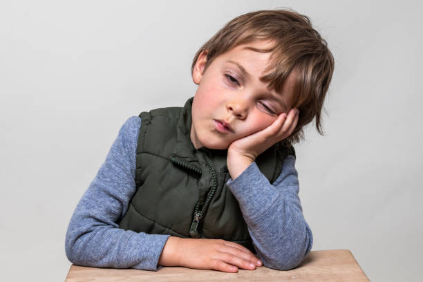 Tired, sleepy, Serious caucasian blond child boy looking at the camera
